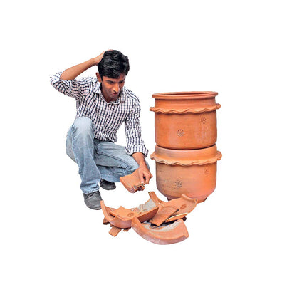 Man sitting with broken unit and lid of terracotta khamba composter